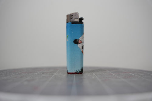 Reverse side of the sky-blue collaged lighter showing a skateboarder mid-trick