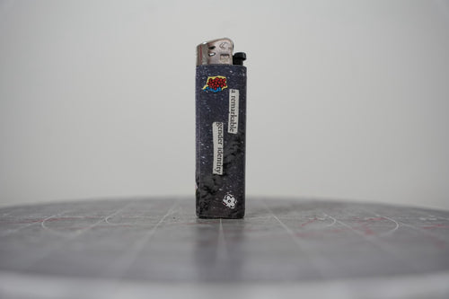 Hand-collaged lighter with navy speckled ground, cut-paper florals and the text "a remarkable gender identity"