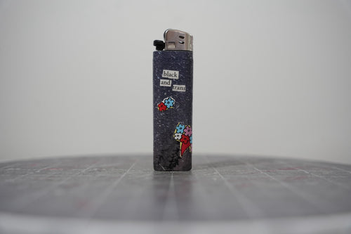 Reverse side of the collaged lighter reading "black and trans" with cut-paper flower bouquets