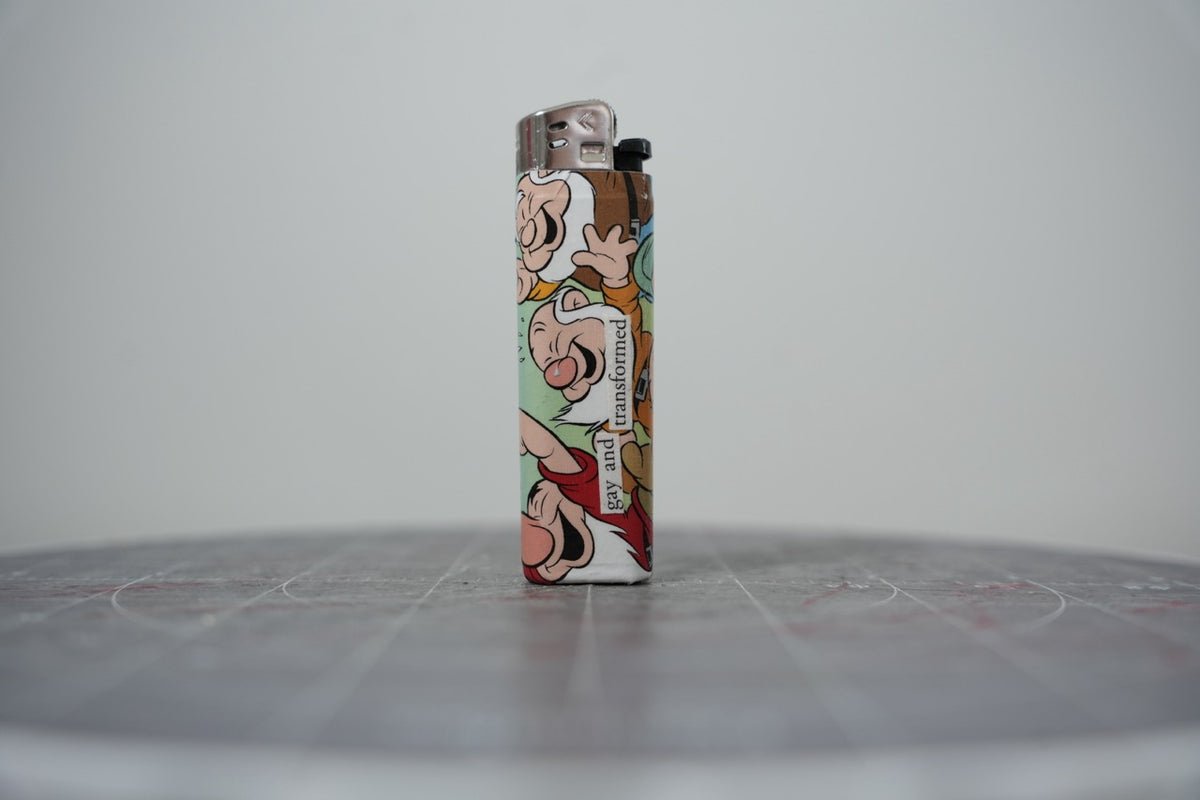 Hand-collaged lighter made from Disney comic book paper, laughing faces with cut-paper text reading "gay and transformed"