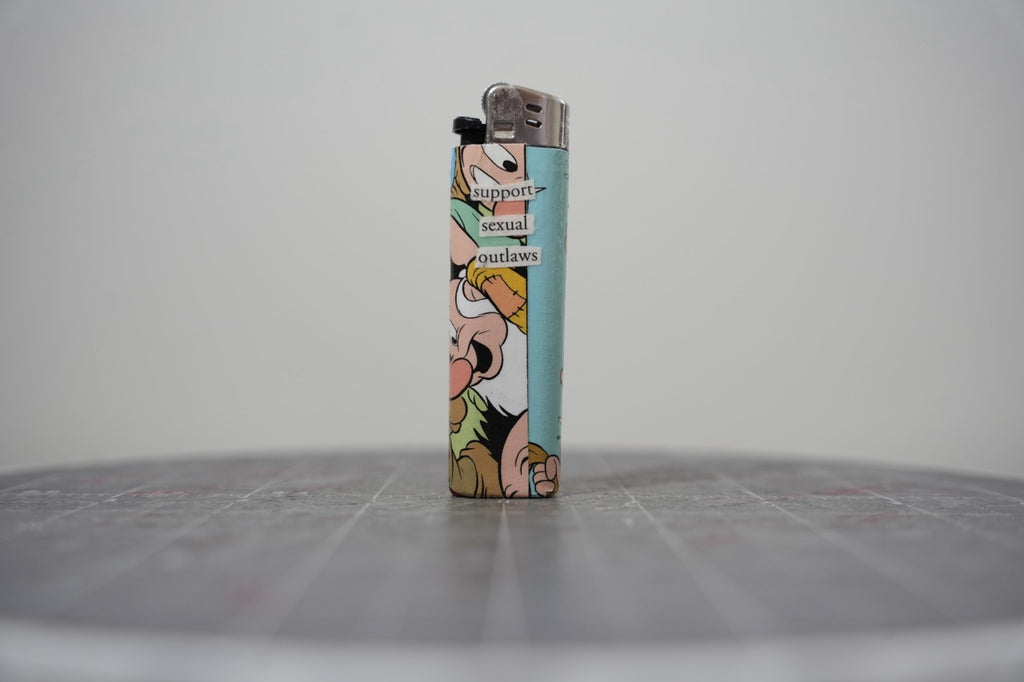Reverse side of the Disney comic collage lighter reading "support sexual outlaws"