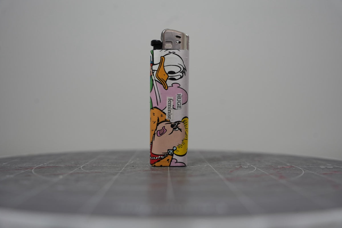 Hand-collaged lighter made from Disney comic book paper with cut-paper text reading "HUGE feminist"