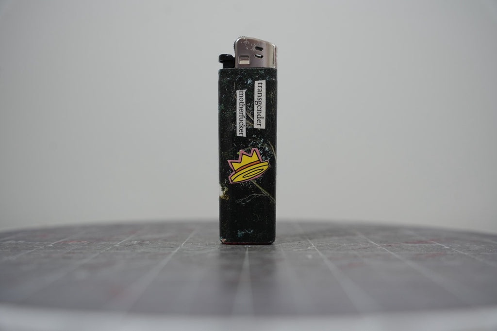 Front of a handmade collage lighter made from vintage Disney comic book paper, glittery black ground with a yellow crown and cut-paper text