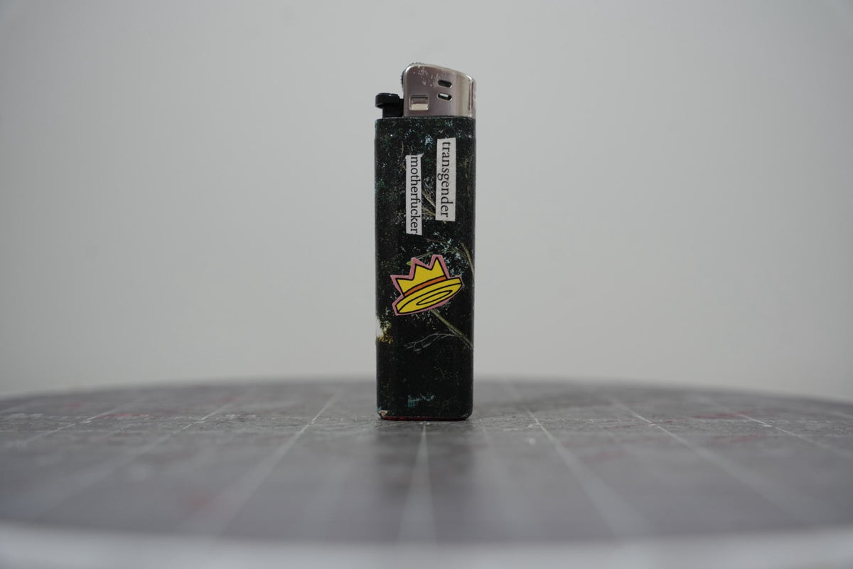 Front of a handmade collage lighter made from vintage Disney comic book paper, glittery black ground with a yellow crown and cut-paper text