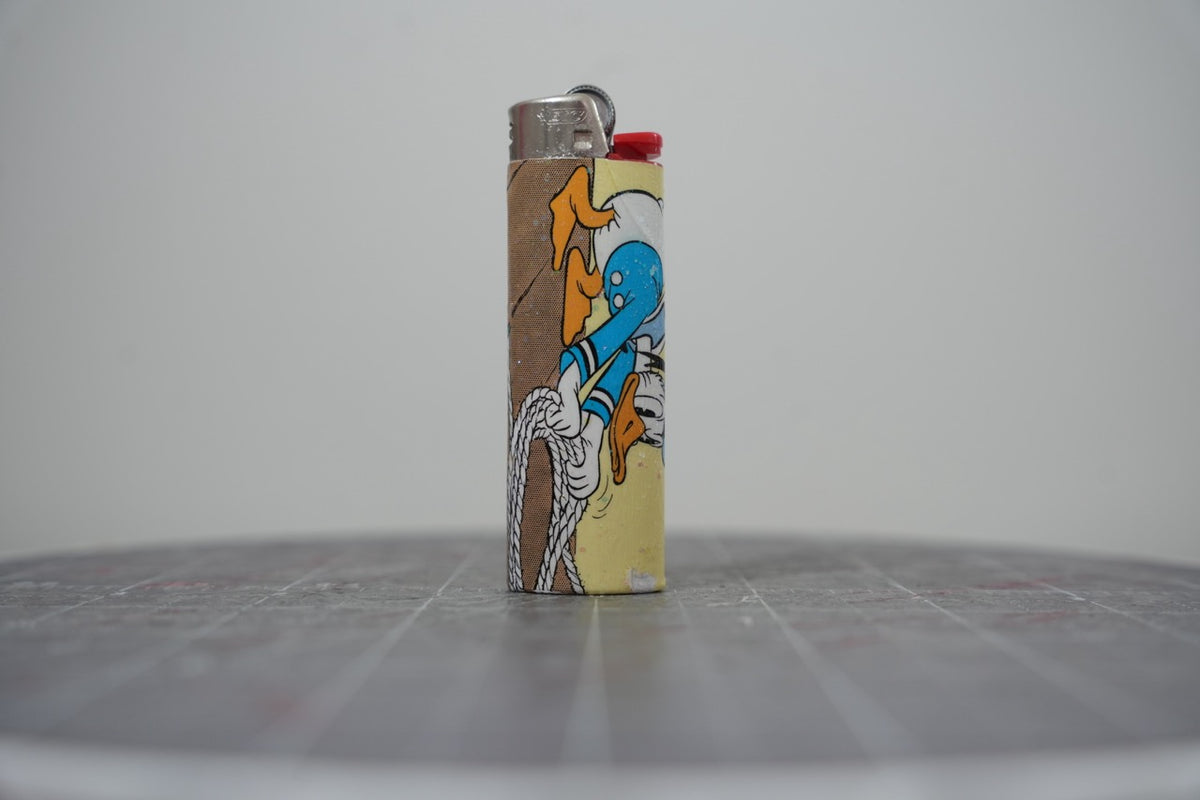 Front of a handmade collage lighter made from vintage Disney comic book paper, Donald Duck with a coil of rope on a yellow glittered ground