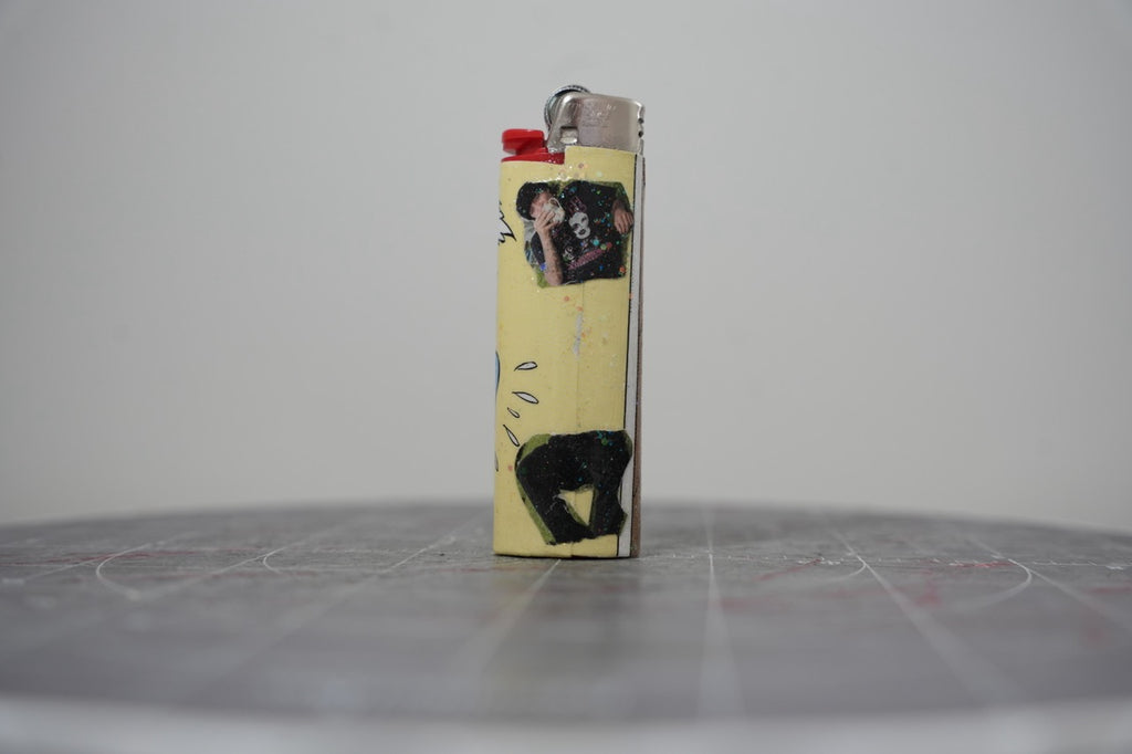 Reverse side of the same Disney comic book collage lighter, pale yellow with photo cut-outs and black glitter shapes