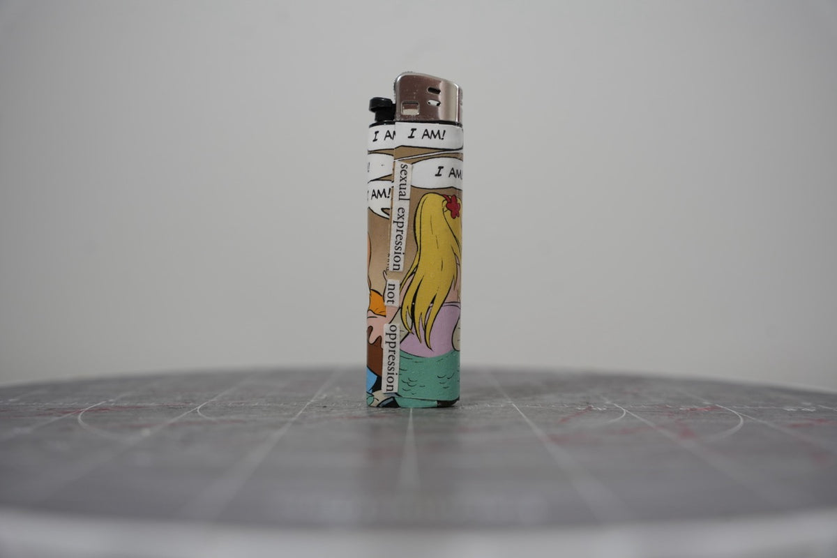 Front of a handmade collage lighter made from vintage Disney comic book paper, cut-paper text reading sexual expression not oppression