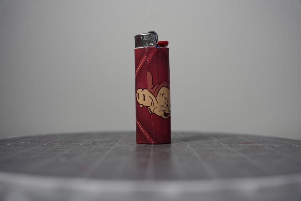 Reverse of the Disney comic book collage lighter showing Dopey's face on dark red