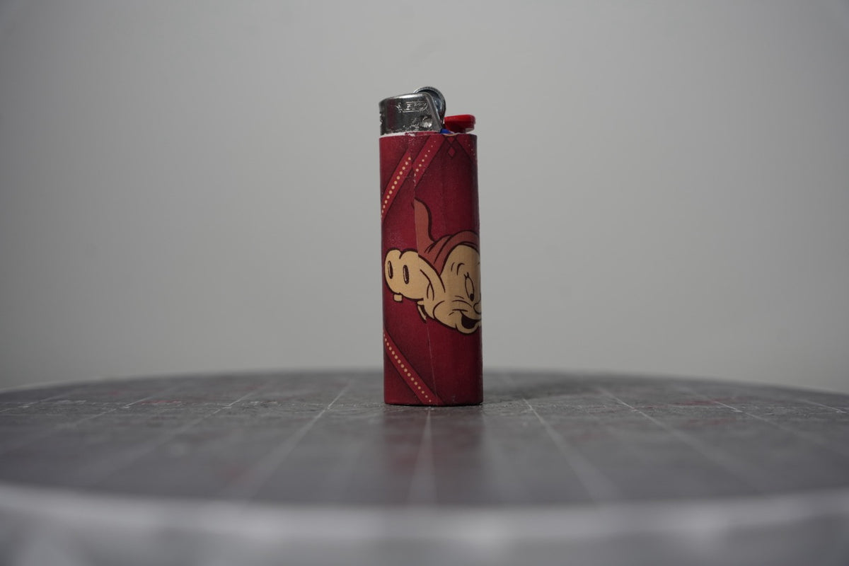 Reverse of the Disney comic book collage lighter showing Dopey's face on dark red