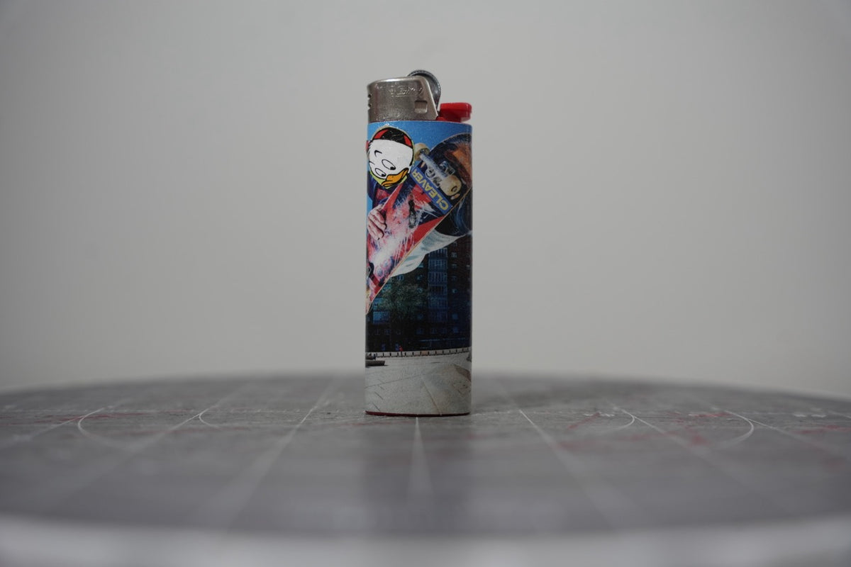 Reverse of the collage lighter showing a cut-out duck head and a Cleaver skate deck