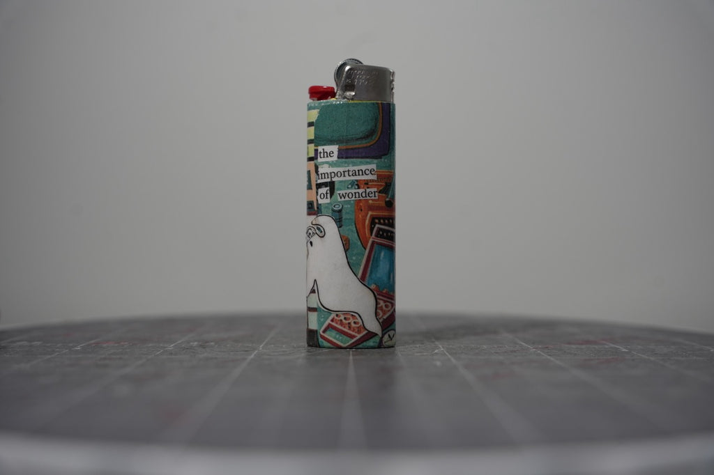 Reverse of the collage lighter showing a white cartoon goose and the words the importance of wonder