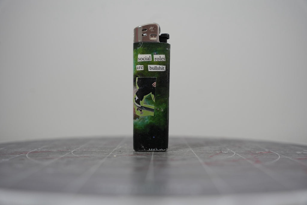 Handmade collage lighter on a green nebula with a skateboarder and the words social roles are bullshit