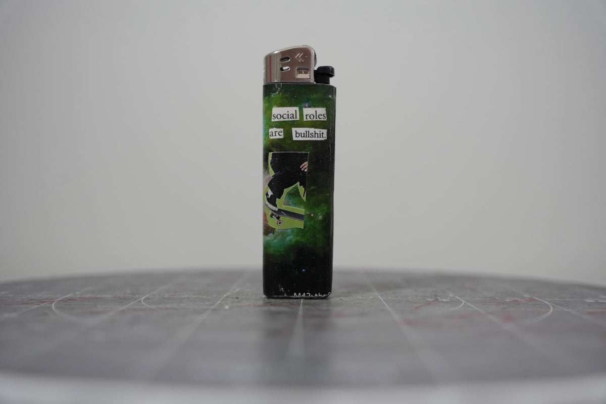Handmade collage lighter on a green nebula with a skateboarder and the words social roles are bullshit