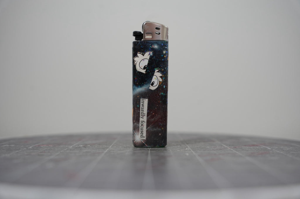 Reverse of the collage lighter, glittered black galaxy with cartoon bird heads and the words inwardly focused