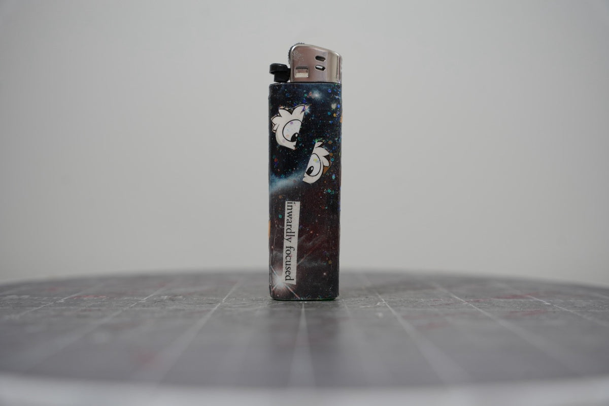 Reverse of the collage lighter, glittered black galaxy with cartoon bird heads and the words inwardly focused