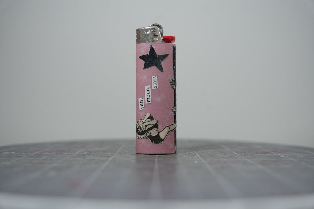 Handmade collage lighter, pink with a black star and the words sun, moon, stars
