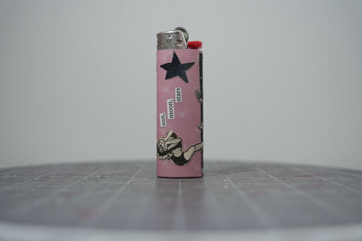 Handmade collage lighter, pink with a black star and the words sun, moon, stars