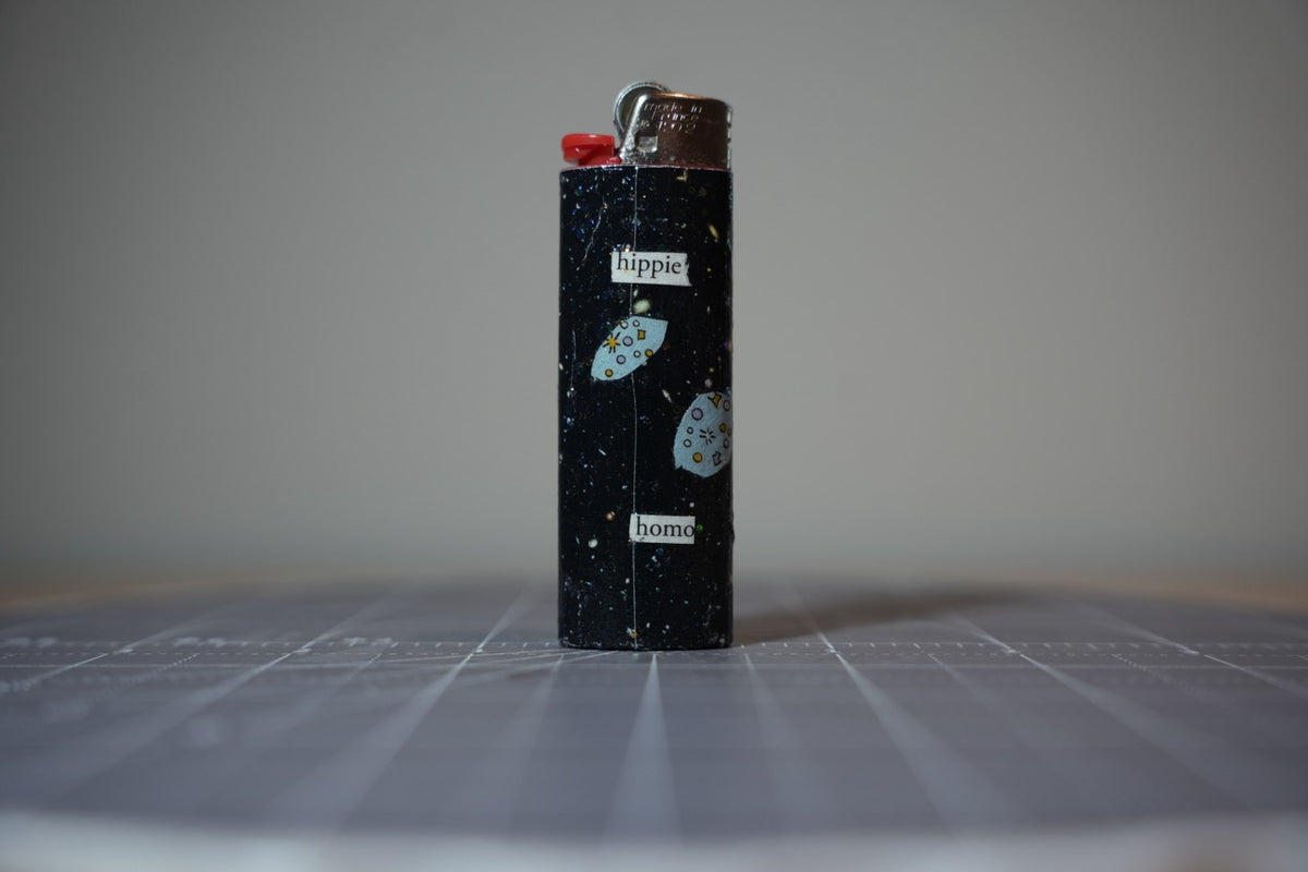 Reverse of the collage lighter showing flying saucers and the words hippie and homo