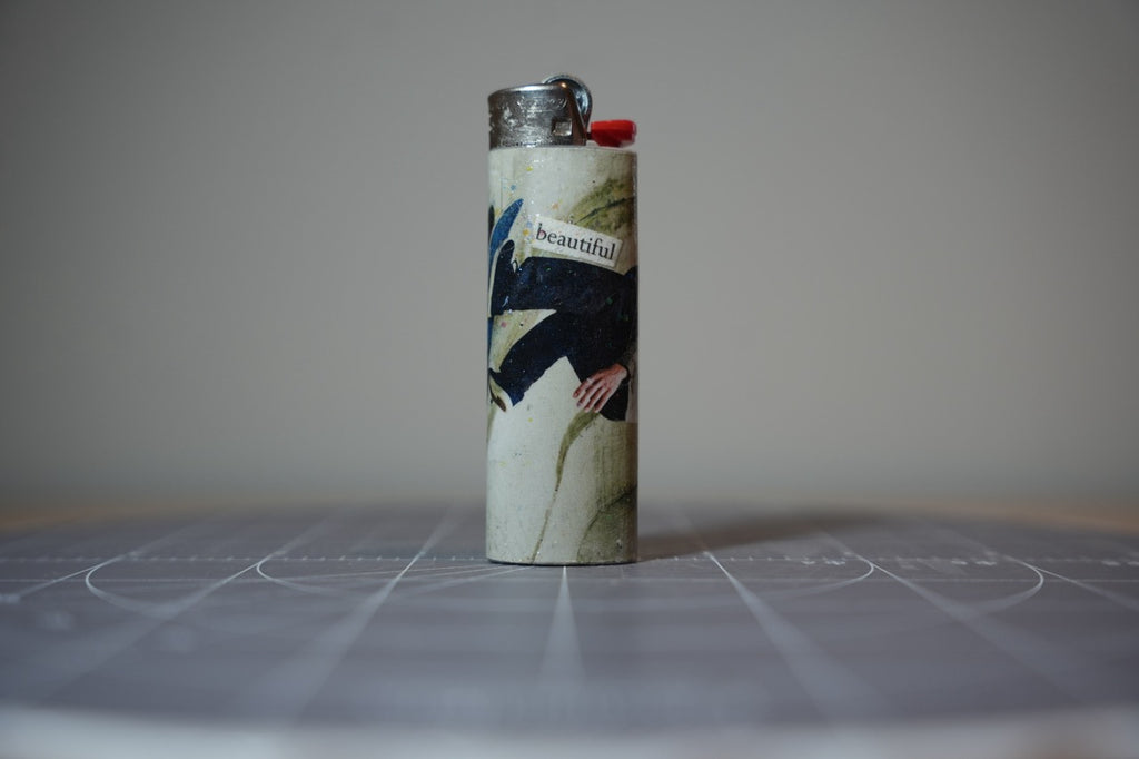 Reverse of the collage lighter showing a man in a navy coat and the word beautiful