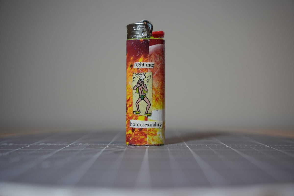 Reverse of the collage lighter showing a cartoon man in a chef's hat and the words I like wood